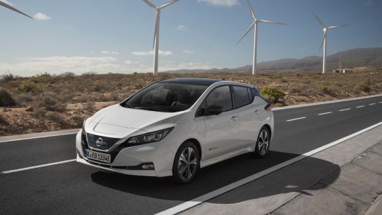 Nissan vehicle driving on road, wind turbines in the background | Dutch Miller Nissan Of Bristol in Bristol TN