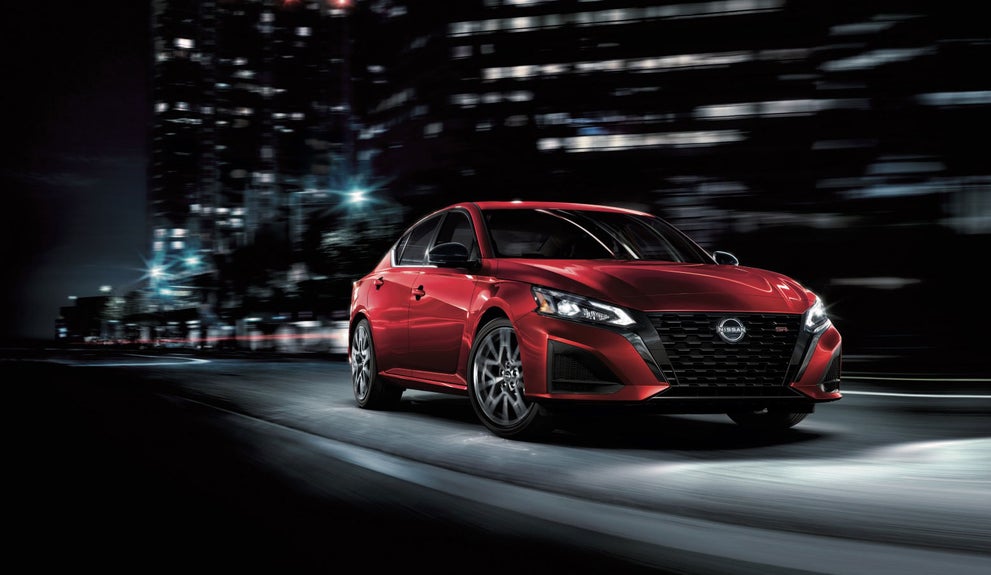 Nissan Altima driving down city street at night